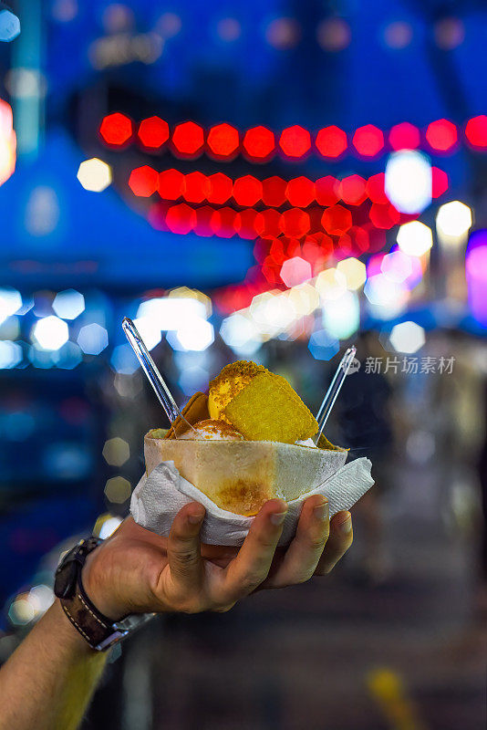 吉隆坡Jalan Alor街头食品市场的灯光下，手拿椰子和芒果冰淇淋